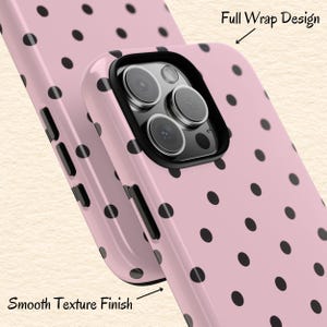 May include: Pink phone case with black polka dots. The case has a smooth texture finish and a full wrap design. The case has a black border around the camera lenses.