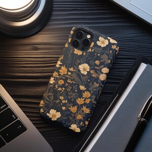 May include: A black phone case with a floral pattern featuring yellow and white flowers on a dark blue background. The case has a camera cutout and a raised lip around the edges.