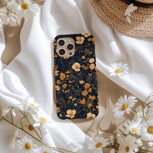 May include: A black phone case with a floral pattern featuring yellow and white flowers on a dark blue background.