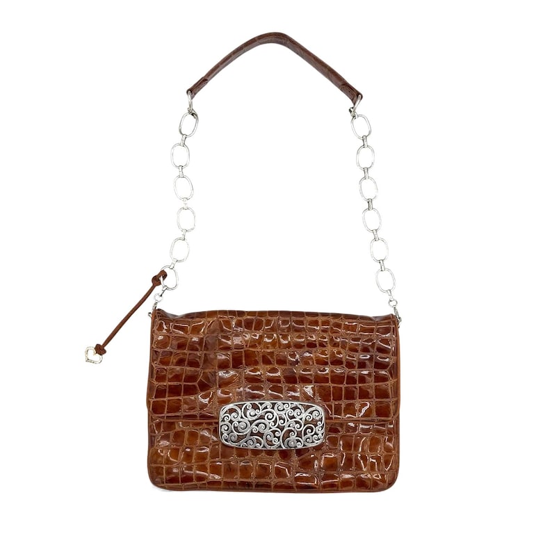 Puede incluir: Bolso de mano marr&oacute;n texturizado con una correa de cadena plateada y un cierre decorativo plateado. El bolso tiene forma rectangular y un asa de cuero. El cierre presenta un dise&ntilde;o ornamental y ondulado. El bolso es de tama&ntilde;o mediano.