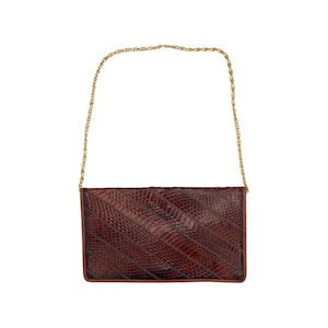 May include: A brown clutch with a gold chain strap. The rectangular bag has a textured, snake-like pattern and a brown border. The chain is a delicate, gold-colored link.
