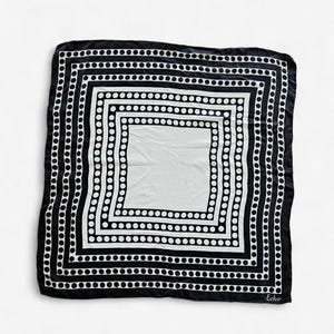 May include: A black and white square scarf with a geometric dot pattern. The scarf has a black border and a white center. The word "Echo" is printed in the bottom right corner.