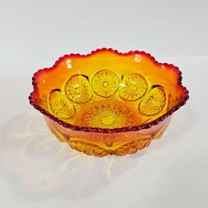 Könnte beinhalten: Eine bernsteinfarbene Glasschale mit gewelltem Rand. Die Schale hat ein Sternmuster auf Boden und Seiten, mit rotem Rand. Die Schale ist wahrscheinlich Vintage und zum Servieren geeignet.