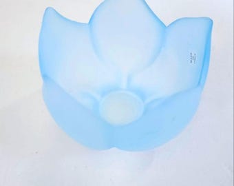 May include: A light blue, frosted glass bowl in the shape of a flower. The bowl has a central, circular base and petal-shaped sides. The words "MADE IN ITALY" are visible on the side of the bowl.