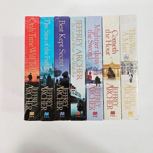 Puede incluir: Una pila de siete libros de bolsillo de Jeffrey Archer. Las lomos de los libros son de varios colores, incluyendo rojo, azul y blanco. Los títulos incluyen "Only Time Will Tell" y "This Was A Man". Cada libro tiene una ilustración de portada diferente.