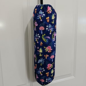 May include: A dark blue fabric bag with a repeating pattern of colorful mushrooms in pink, yellow, and blue. The bag is hanging from a black loop and appears to be made of soft material.