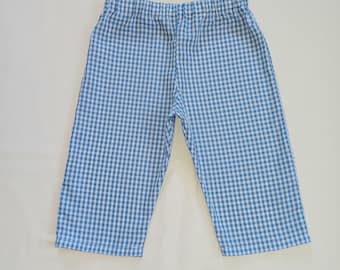 May include: Blue and white gingham patterned pants. The pants have an elastic waistband and a relaxed fit. The fabric is a light, breathable material, perfect for warm weather. The pants are laid flat on a white surface.