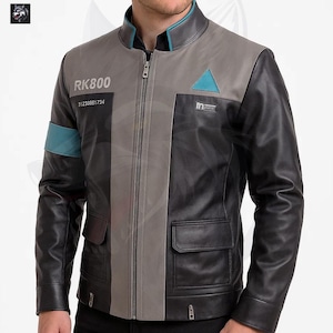 May include: A black, grey, and teal leather jacket with a zip-up front. The jacket features the text "RK800" and "31233881734" on the left chest, and a teal triangle on the right chest. The jacket has two front pockets.