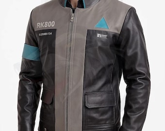 Puede incluir: Chaqueta de cuero negra, gris y verde azulado con cremallera. La chaqueta presenta el texto "RK800" y "31233881734" en el pecho izquierdo, y un triángulo verde azulado en el pecho derecho. La chaqueta tiene dos bolsillos delanteros.