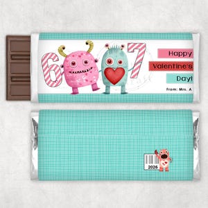 May include: A chocolate bar with a Valentine's Day theme. The wrapper features two cartoon monsters, the number 6 and 7, and the text "Happy Valentine's Day!" in pink and white. The back of the wrapper has a teal grid pattern.
