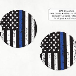 May include: Two car coasters with a distressed American flag design. The flag features a blue line, white stars on a black background, and black and white stripes. Text on the image reads "CAR COASTERS".