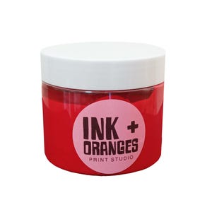 May include: A red jar of ink with a white lid and a pink circle label that says "INK + ORANGES PRINT STUDIO".
