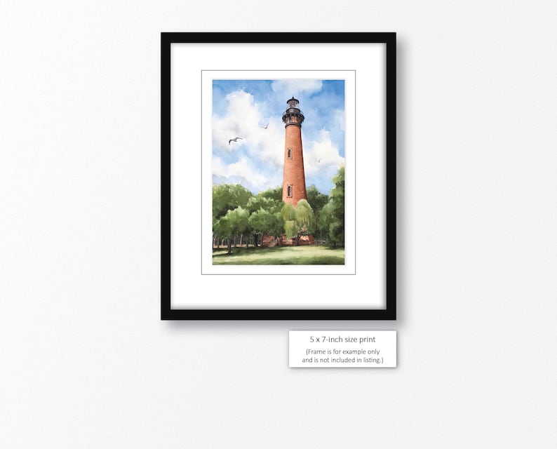 May include: Watercolor painting of a red brick lighthouse with a white trim and a black roof. The lighthouse is surrounded by green trees and a blue sky with white clouds. The text "5 x 7-inch size print (Frame is for example only and is not included in listing.)" is at the bottom of the image.