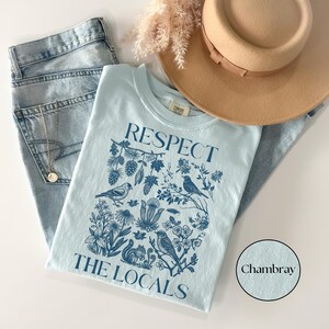 Vintage wildlife graphic T-shirt reading Respect The Locals with botanical forest illustration and birds, cozy nature lover Comfort Colors chambray shirt.