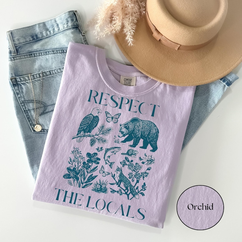 Granola girl aesthetic wildlife graphic tee in orchid featuring woodland animals, botanical elements, and conservation-inspired “Respect The Locals” artwork.