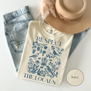 Ivory Comfort Colors shirt with Respect The Locals nature graphic featuring birds, forest plants, pinecones, and squirrel illustration, granola girl aesthetic tee.