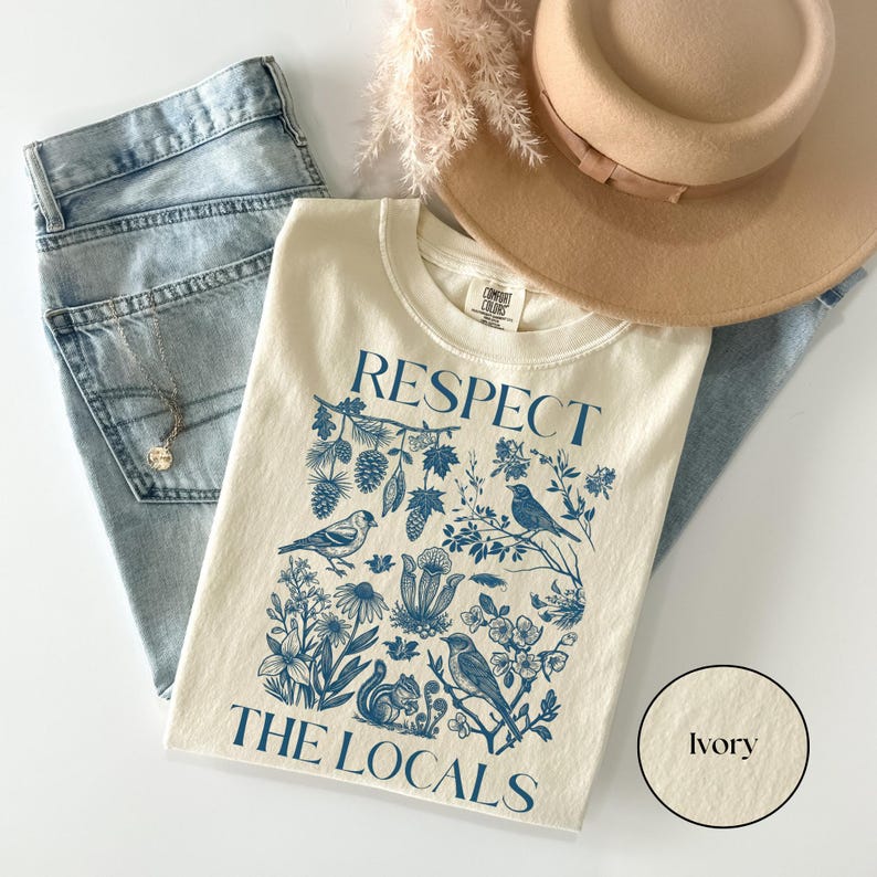 Ivory Comfort Colors shirt with Respect The Locals nature graphic featuring birds, forest plants, pinecones, and squirrel illustration, granola girl aesthetic tee.