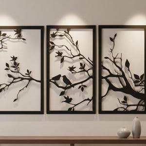 May include: Three-piece wall art set featuring black metal silhouettes of tree branches and birds against a white background. Each framed panel has a rectangular shape. The artwork is displayed above a wooden console.