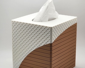 May include: A white tissue box holder with a brown and white geometric pattern. The holder has a square shape and a rectangular opening for tissues.