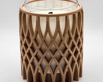 May include: A candle in a clear glass jar, encased in a decorative brown wooden lattice. The lattice has a repeating diamond pattern. The candle is white and appears to be unscented. The candle holder is cylindrical and sits on a white surface.