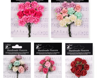 Puede incluir: Cinco paquetes de flores de papel hechas a mano. Cada paquete contiene un ramo de pequeñas flores delicadas en una variedad de colores, incluyendo rosa, rojo, blanco y verde. Las flores están dispuestas sobre un fondo blanco con notas musicales impresas en él. El empaque incluye el texto "Little Birdie Handmade Flowers".
