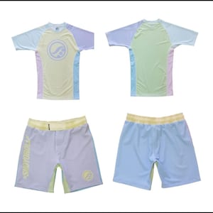 Könnte beinhalten: Ein pastellfarbenes Sport-Set mit einem kurzärmeligen Shirt und Shorts. Das Shirt hat ein kreisförmiges Design auf der Vorderseite und die Shorts tragen den Text "SHOYOROLL" auf der Seite. Das Set ist hauptsächlich gelb, blau und lila.