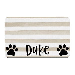 May include: Beige and white striped doormat with black paw prints on either side and the name "Duke" in black cursive lettering.