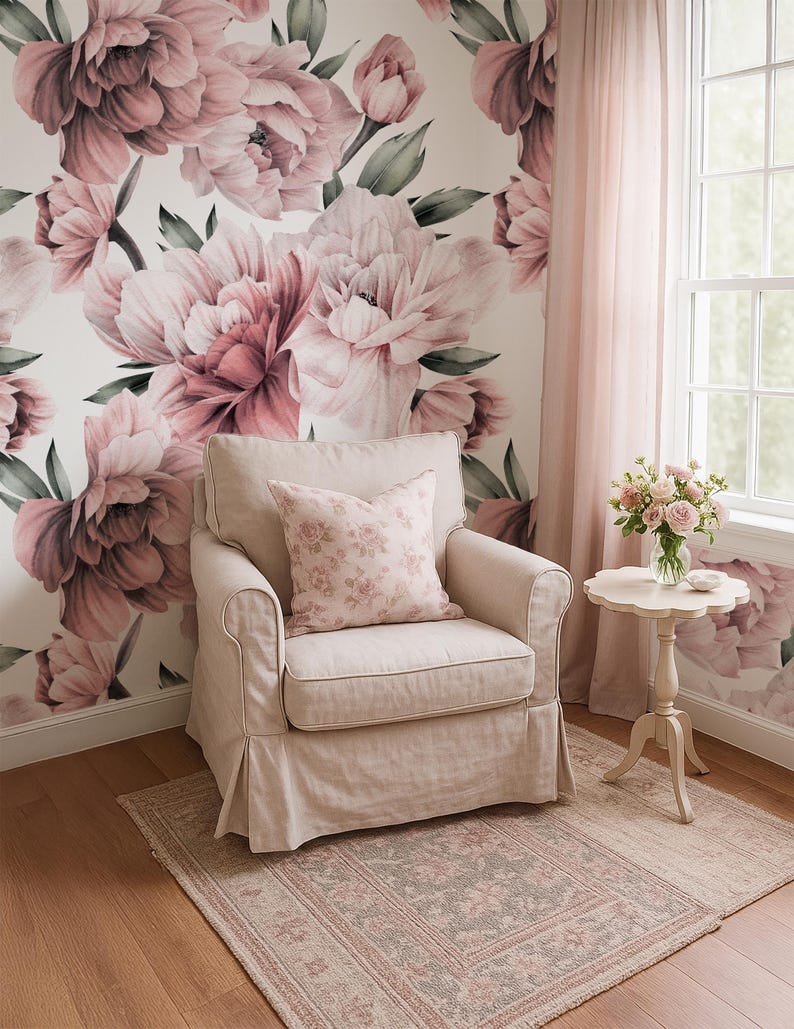 May include: A living room with a floral peony wallpaper in shades of pink. A beige armchair with a floral cushion sits on a patterned rug. A small side table holds a vase of roses, creating a soft, inviting atmosphere.