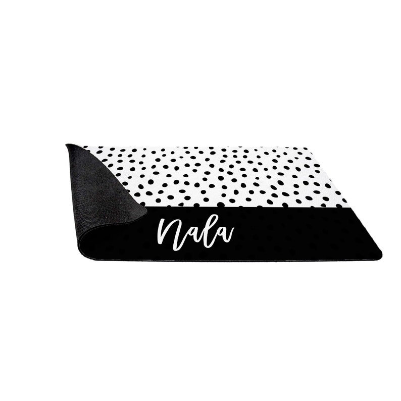 May include: Black and white doormat with a black and white polka dot pattern and the name "Nala" written in white on a black background.