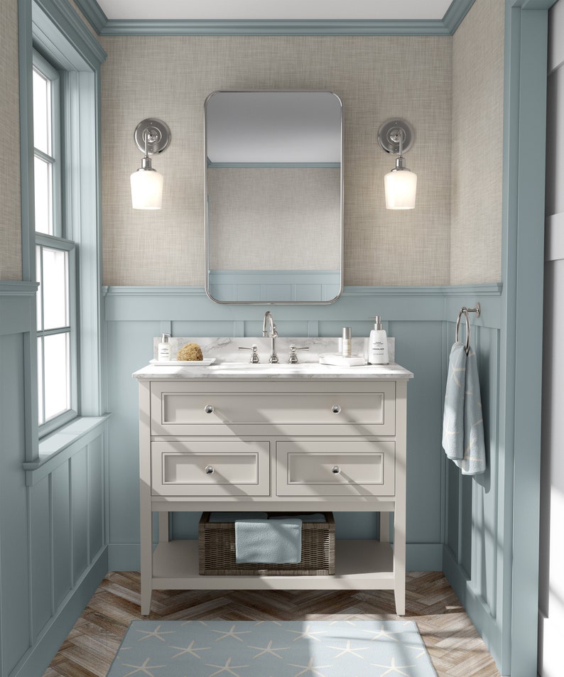 May include: A white bathroom vanity with three drawers and a lower shelf. The vanity has a white marble countertop with a chrome faucet and two chrome sconces with white glass shades on either side of a rectangular mirror.