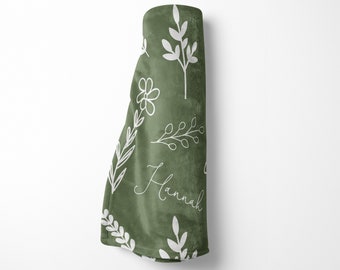May include: A green baby blanket with a white floral pattern and the name "Hannah" written in cursive.