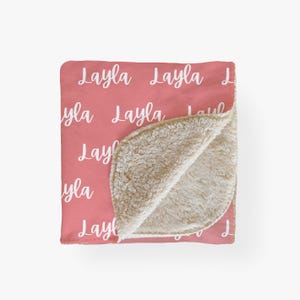 May include: A pink fleece blanket with the name "Layla" repeated in white text.