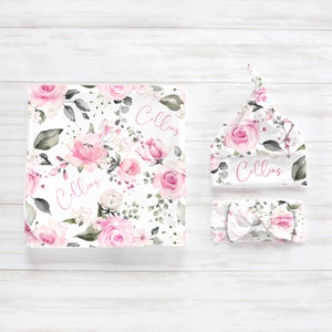 May include: A baby blanket, hat, and headband set. The items feature a floral pattern with pink roses, green leaves, and the name "Collins" in pink script. The set is designed for newborns.