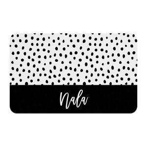May include: Black and white doormat with a white background and black polka dots. The bottom half of the doormat is black with the name "Nala" written in white.