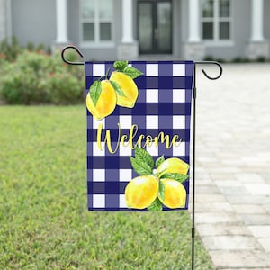 May include: A blue and white gingham garden flag with lemons and the word "Welcome" printed on it.