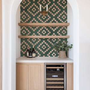 May include: A built-in bar area with a white countertop and wooden cabinets. The back wall is covered in green and brown patterned wallpaper. There is a small wine fridge with a glass door and shelves for storing wine bottles.