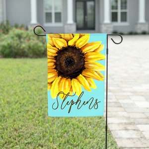 May include: A blue and yellow garden flag with a watercolor sunflower and the name "Stephens" written in cursive.
