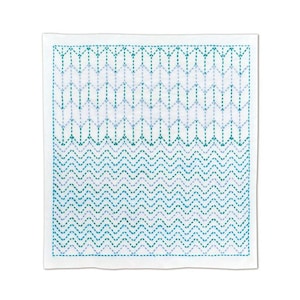 Op de afbeelding: Vierkante witte doek met een geborduurd patroon. Het ontwerp toont rijen gestikte chevrons en verticale lijnen in teal en lichtblauw, waardoor een getextureerde, geometrische uitstraling ontstaat. Waarschijnlijk een decoratief textiel.