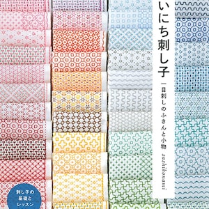 May include: A display of fabric rolls with diverse sashiko embroidery patterns. The image includes a book with Japanese text and a blue circle with Japanese text. The fabrics exhibit geometric and floral designs in red, pink, blue, and green, showcasing traditional Japanese craft.
