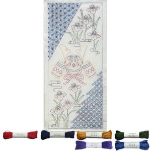 May include: Embroidered Japanese panel featuring a samurai helmet, irises, and geometric patterns in blue, orange, and green thread. Several spools of thread in various colours are at the bottom. The panel is white.