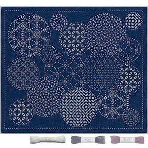 Könnte beinhalten: Ein marineblaues Textil mit weißen geometrischen Mustern in verschiedenen kreisförmigen Formen. Das Design ist mit weißem Faden gestickt. Drei Garnrollen in Weiß, Grau und Mauve befinden sich unten. Das Textil ist quadratisch.