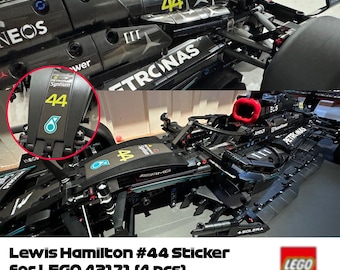 Pode incluir: Um conjunto de quatro adesivos pretos e amarelos para o carro de Fórmula 1 LEGO 42171 Lewis Hamilton. Os adesivos apresentam o número 44, o logotipo da Petronas e o logotipo da Mercedes-AMG.