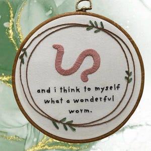 Puede incluir: Un juego de tres tazas de cerámica con un esmalte moteado de color crema. Cada taza presenta un diseño pintado a mano diferente: una hoja azul y verde, una flor amarilla y una baya roja. Las tazas tienen una forma simple y redondeada.