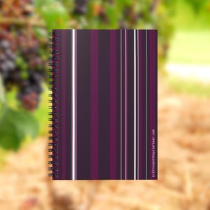 May include: A spiral-bound notebook with a vertical striped pattern in shades of purple and white. The notebook's cover features alternating stripes of dark purple, lighter purple, and white. The text "brittniandthepolarbear.com" is printed on the bottom right.