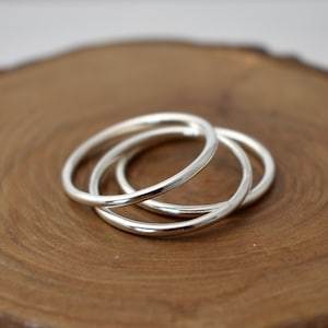May include: Three silver stacking rings, each with a smooth, polished finish. The rings are arranged in a stack, with the largest ring on the bottom and the smallest ring on top.