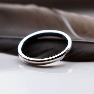 May include: A simple silver band ring with a smooth, rounded surface.