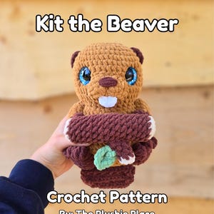 Puede incluir: Un peluche de castor tejido a ganchillo con el texto "Kit the Beaver" encima. El castor tiene pelaje marrón, ojos azules y un diente blanco. Sostiene un tronco tejido a ganchillo marrón y verde. El texto "Crochet Pattern By: The Plushie Place" está debajo.