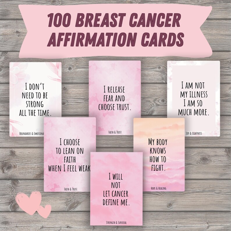Puede incluir: Un conjunto de 100 tarjetas de afirmaci&oacute;n sobre el c&aacute;ncer de mama. Las tarjetas presentan varias afirmaciones en texto blanco sobre un fondo de acuarela rosa. Las tarjetas est&aacute;n dispuestas sobre una superficie de madera con una pancarta rosa en la parte superior.