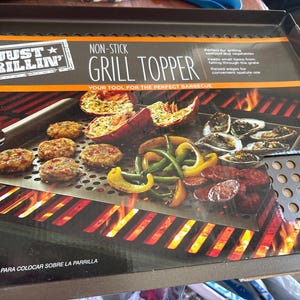 May include: A non-stick grill topper with the text "JUST GRILLIN' GRILL TOPPER". The image shows grilled food including burgers, vegetables, and seafood. The grill topper is designed for the perfect barbecue.