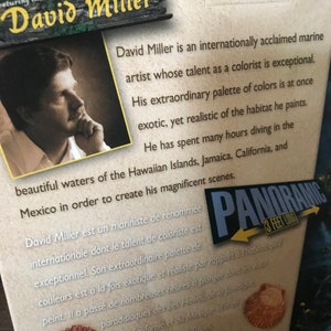 May include: A box for a 3-foot long panoramic jigsaw puzzle featuring the artwork of David Miller. The box features a portrait of the artist and text describing his work as an internationally acclaimed marine artist. The text describes his talent as a colorist and his use of color to depict the underwater world.